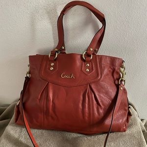 Burnt Orange / Rust Coach satchel with snap closure and shoulder strap.